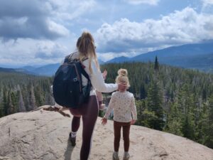 a woman and child on a rock overlooking a forest