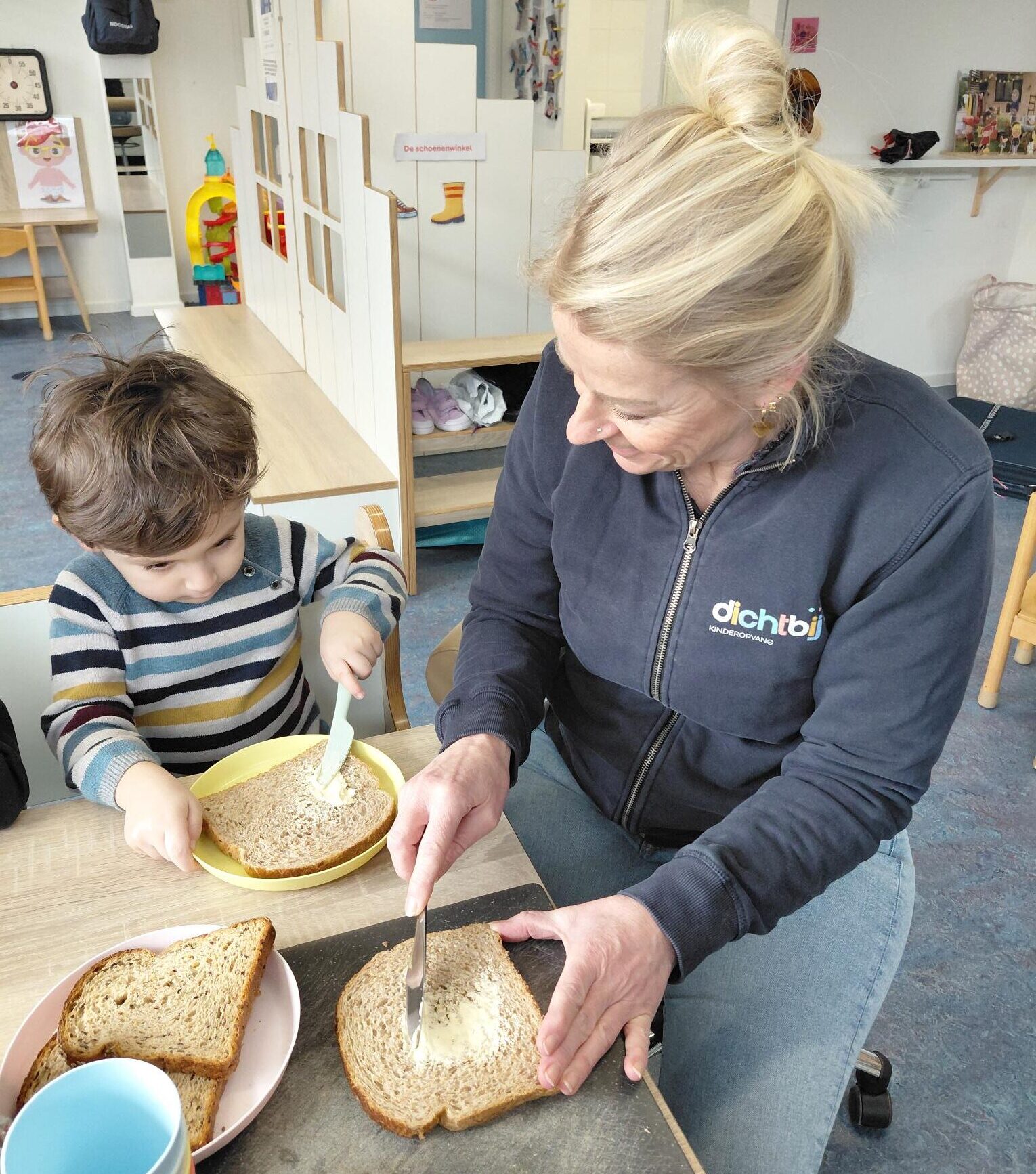 pedagogisch professional helpt peuter bij eten en drinken